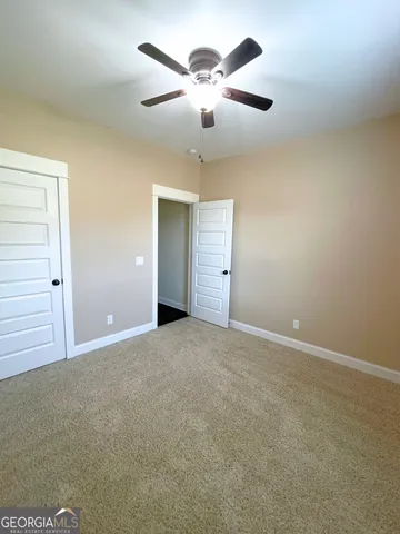 an empty room with chandelier fan and windows