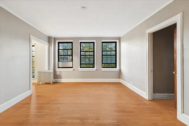 a view of an empty room with window and wooden floor
