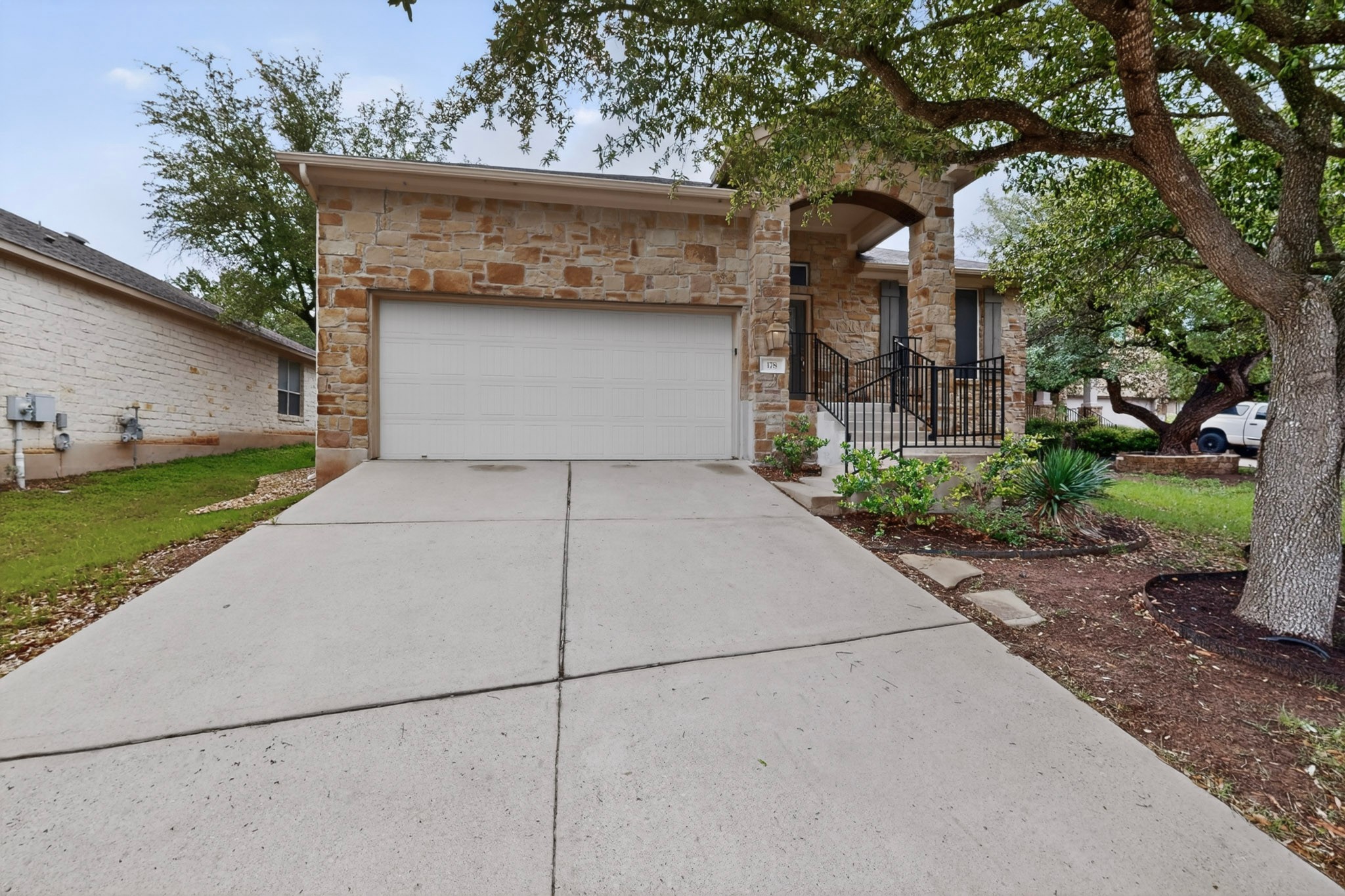 178 Limestone Trail Austin, TX 78737 - Photo 2 of 40 Stone-clad exterior featuring a prominent two-car garage, concrete driveway, and covered front entry