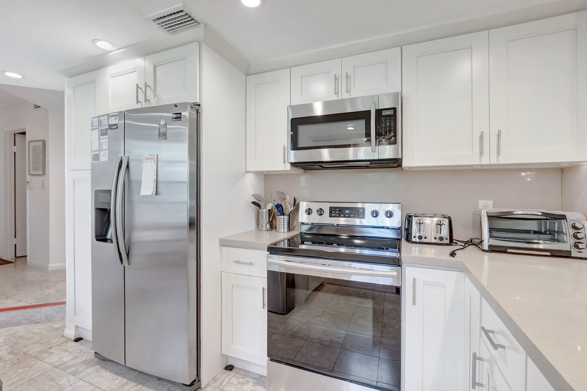 7950 La Mirada Drive Boca Raton, FL 33433 - Photo 11 of 42 a kitchen with stainless steel appliances a stove a microwave and a refrigerator