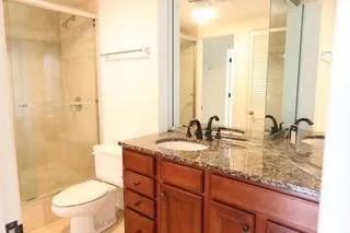 a bathroom with a granite countertop sink mirror vanity and toilet