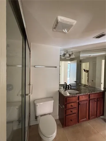 a bathroom with a granite countertop sink toilet mirror and a bathtub