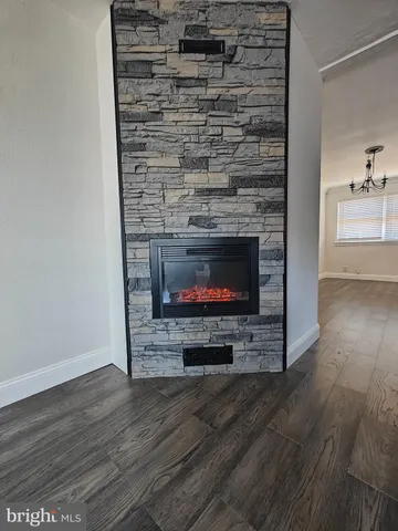 a living room with stainless steel appliances wooden floor and a fireplace