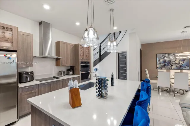 a kitchen with stainless steel appliances a sink a kitchen island a stove a table and chairs