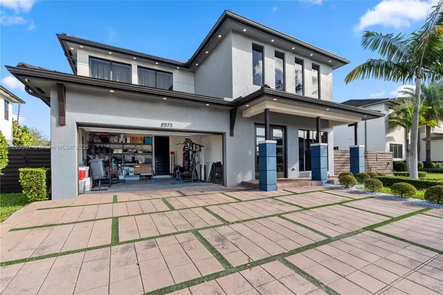 a view of a house with a yard plants and large tree