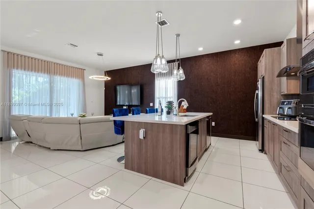 a kitchen with kitchen island granite countertop a sink and a refrigerator