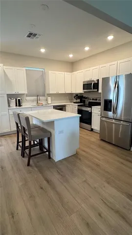 a kitchen with stainless steel appliances kitchen island granite countertop a table chairs and a refrigerator