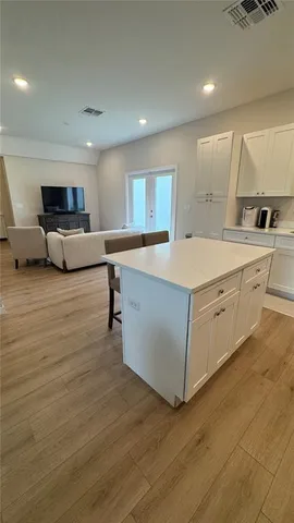 a large white kitchen with kitchen island a sink and a stove top oven