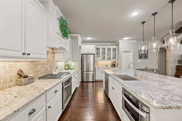 a large kitchen with stainless steel appliances granite countertop a lot of counter space and wooden floors