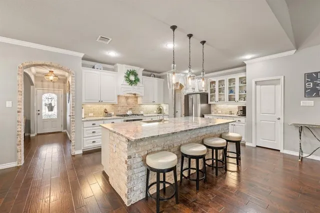 a kitchen with stainless steel appliances kitchen island granite countertop a table chairs and a sink