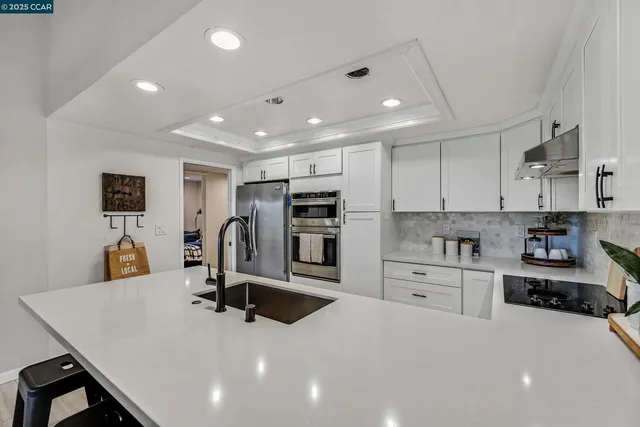 a view of a kitchen with kitchen island a sink stainless steel appliances and cabinets
