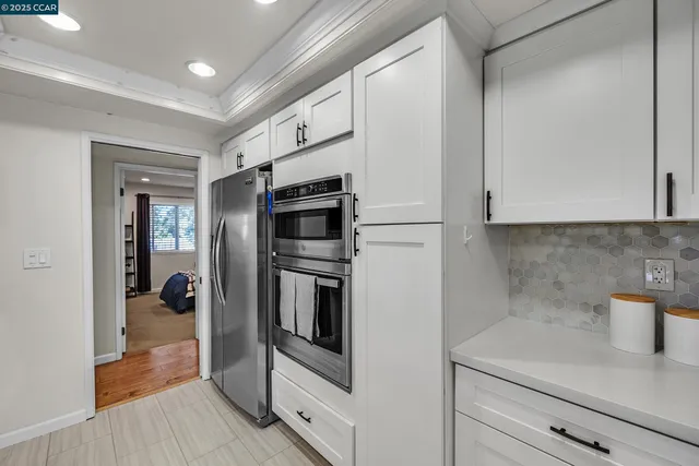 a kitchen with stainless steel appliances white cabinets and wooden floor
