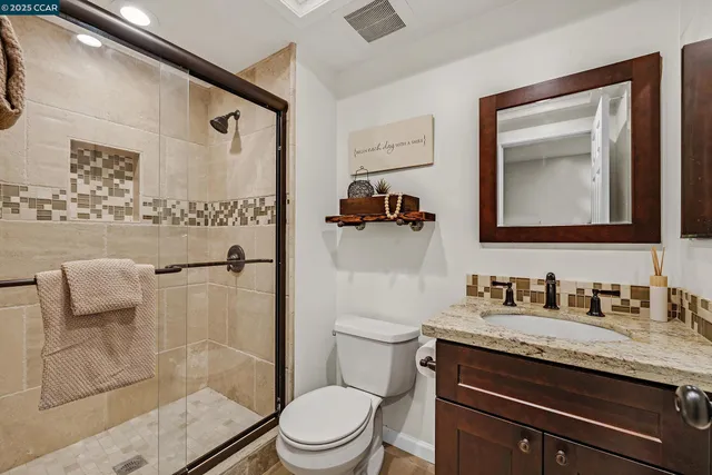 a bathroom with a granite countertop sink a mirror a toilet and shower