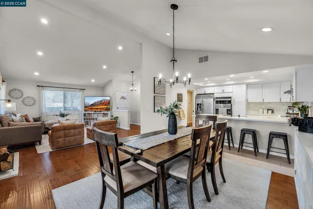 a view of a dining room and livingroom with furniture wooden floor a chandelier