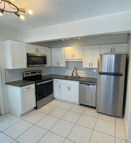 a kitchen with granite countertop a refrigerator and a sink