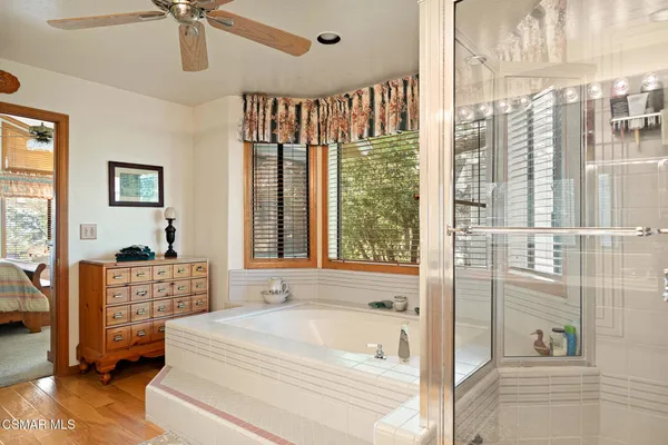 a spacious bathroom with a tub shower and windows