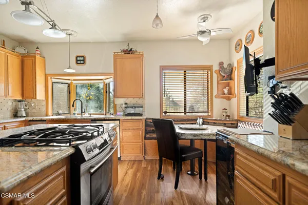 a kitchen with stainless steel appliances granite countertop a stove a sink dishwasher a dining table and chairs with wooden floor