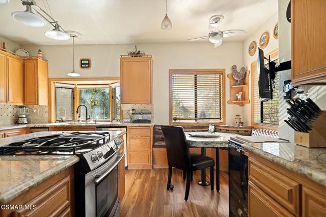 a kitchen with stainless steel appliances granite countertop a stove a sink dishwasher a dining table and chairs with wooden floor