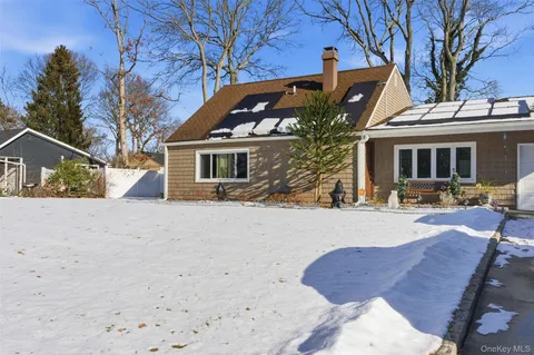 a front view of a house with a yard covered with snow and trees