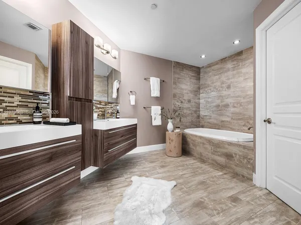 a spacious bathroom with a double vanity sink a mirror and a bathtub