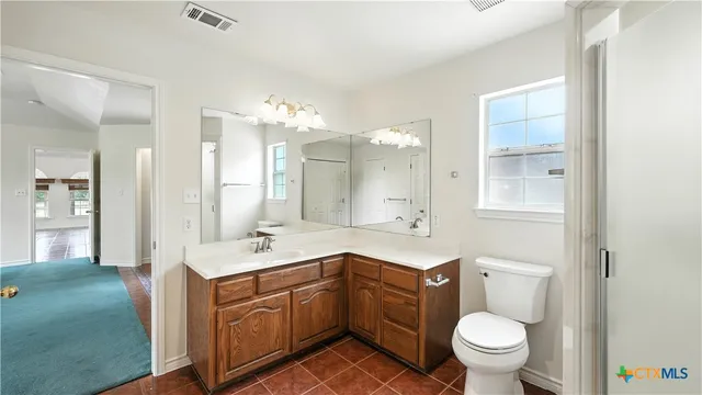 a spacious bathroom with a sink a toilet a mirror and vanity