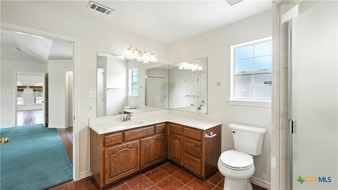 220 Lanier Ranch Road Driftwood, TX 78619 - Photo 17 of 48 a spacious bathroom with a sink a toilet a mirror and vanity