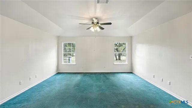 an empty room with windows and fan