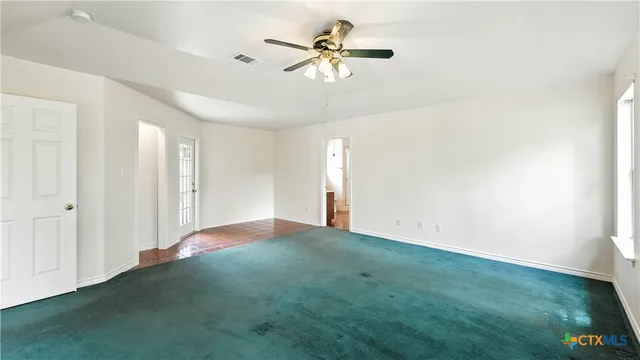 a view of a big room with windows and chandelier fan