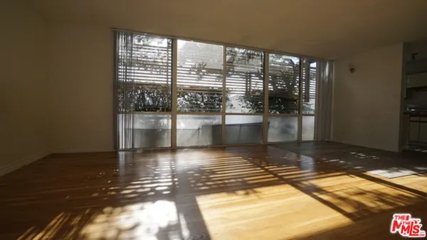 a view of empty room with wooden floor and floor to ceiling window