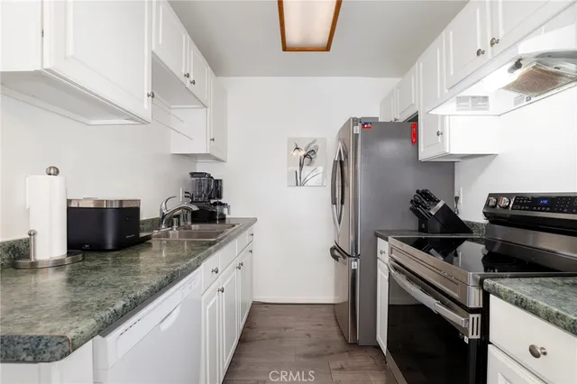 a kitchen with granite countertop a sink stove and refrigerator