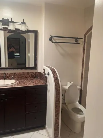 a bathroom with a granite countertop sink toilet and mirror