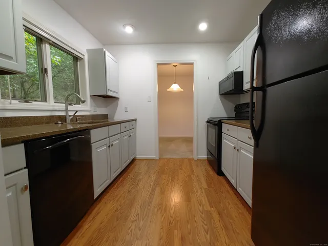 a kitchen with granite countertop a sink a counter top space stainless steel appliances a window and a counter space