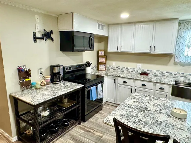 a kitchen with kitchen island granite countertop a sink appliances and cabinets