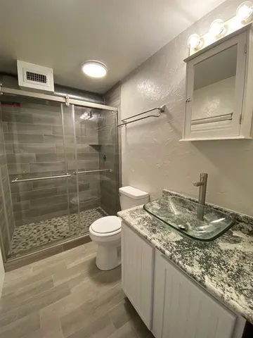 a bathroom with a granite countertop sink a toilet and shower