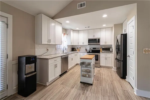 a kitchen with granite countertop a refrigerator stove top oven and sink