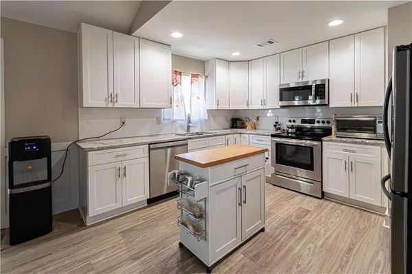 a kitchen with white cabinets stainless steel appliances and sink
