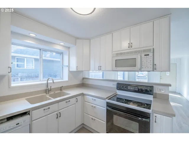 a kitchen with cabinets appliances a sink and a window