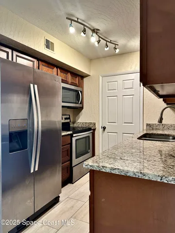 a kitchen with stainless steel appliances granite countertop a refrigerator a stove and a sink with wooden floor