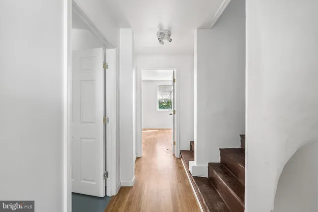 a view of a hallway with wooden floor and a bathroom