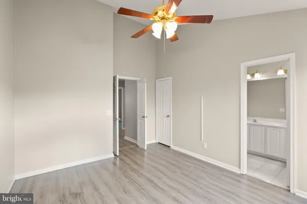 an empty room with wooden floor closet and fan
