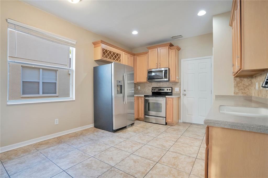 15031 Skip Jack Loop Lakewood Ranch, FL 34202 - Photo 8 of 27 a kitchen with granite countertop a refrigerator and a stove top oven