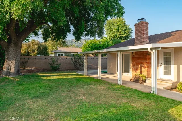 a view of a house with a backyard and a large tree