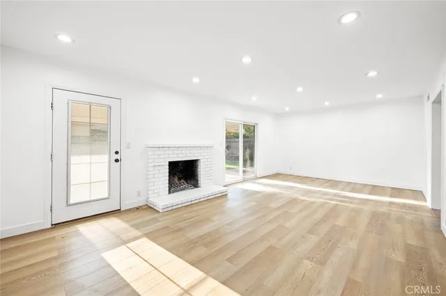 a view of empty room with wooden floor and fireplace