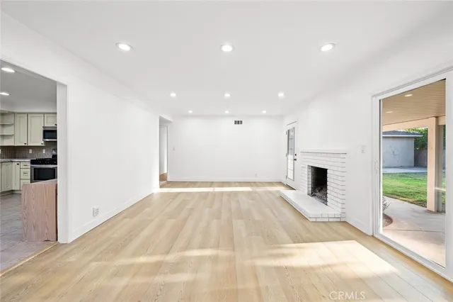 a view of an empty room with kitchen and a window