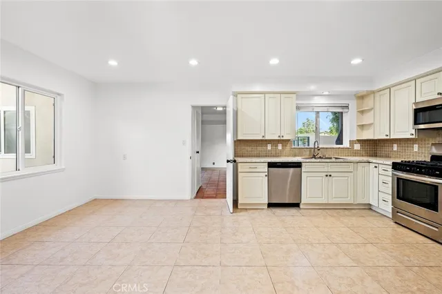 a kitchen with kitchen island granite countertop white cabinets white stainless steel appliances with a sink and dishwasher