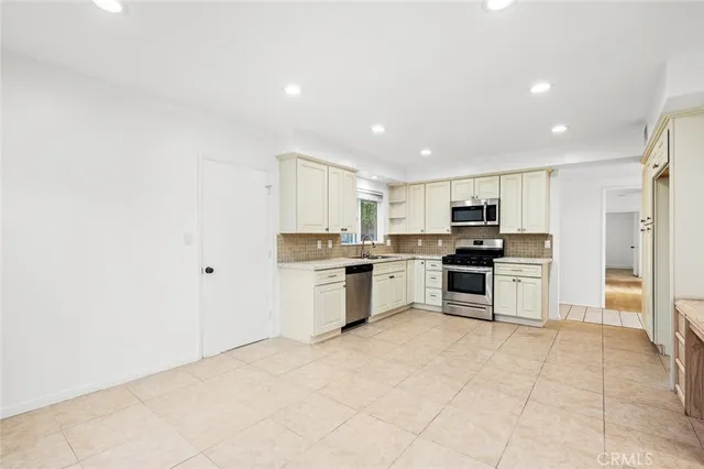 a large kitchen with stainless steel appliances granite countertop a stove a sink and a refrigerator