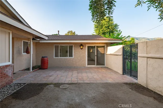 a view of house with backyard and trees in the background
