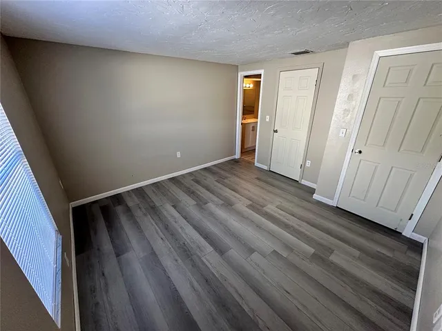 a view of an empty room with wooden floor and closet
