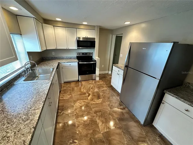 a kitchen with stainless steel appliances a refrigerator sink and microwave