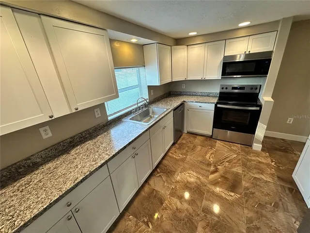 a kitchen with stainless steel appliances granite countertop a sink and a stove